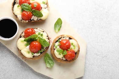 Photo of Tasty stuffed mushrooms served on light table, top view. Space for text