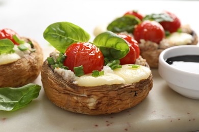 Photo of Tasty stuffed mushrooms served on light table, closeup
