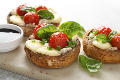Photo of Tasty stuffed mushrooms served on light table, closeup
