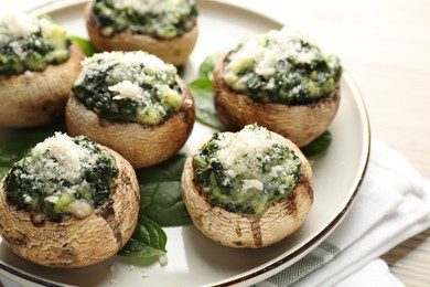Photo of Tasty stuffed mushrooms served on light wooden table, closeup