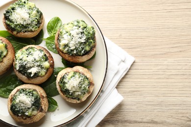 Photo of Tasty stuffed mushrooms served on light wooden table, top view. Space for text