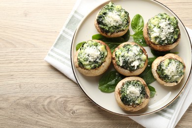 Photo of Tasty stuffed mushrooms served on light wooden table, top view. Space for text