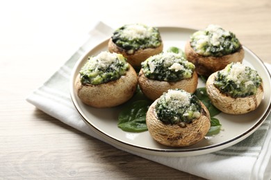 Photo of Tasty stuffed mushrooms served on light wooden table, closeup