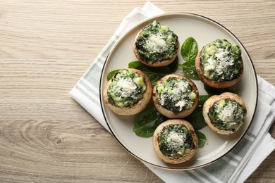 Photo of Tasty stuffed mushrooms served on light wooden table, top view. Space for text