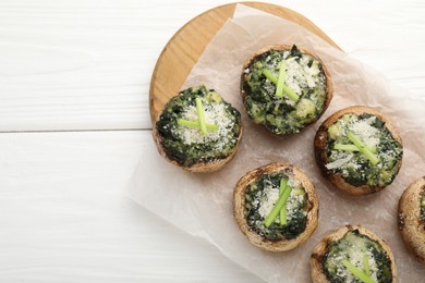Photo of Tasty stuffed mushrooms served on white wooden table, top view. Space for text