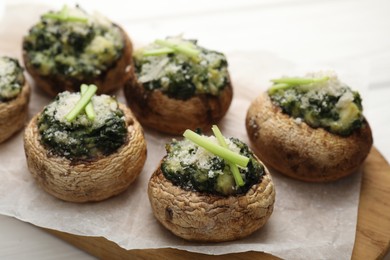 Photo of Tasty stuffed mushrooms served on white wooden table, closeup