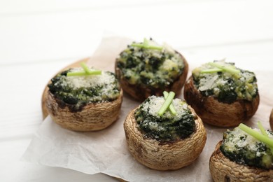 Photo of Tasty stuffed mushrooms served on white wooden table, closeup