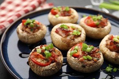 Photo of Tasty stuffed mushrooms served on black table, closeup