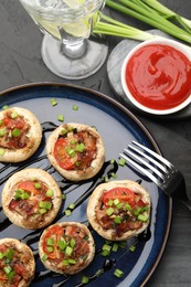 Photo of Tasty stuffed mushrooms served on black table, flat lay
