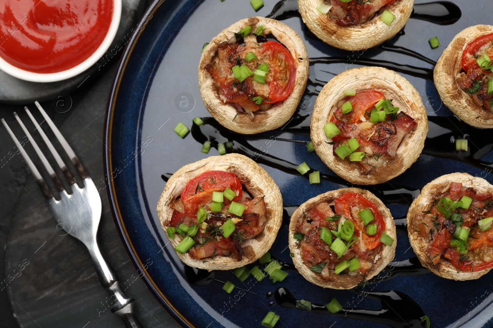 Tasty stuffed mushrooms served on black table, flat lay Photo of Tasty stuffed mushrooms served on black table, flat lay