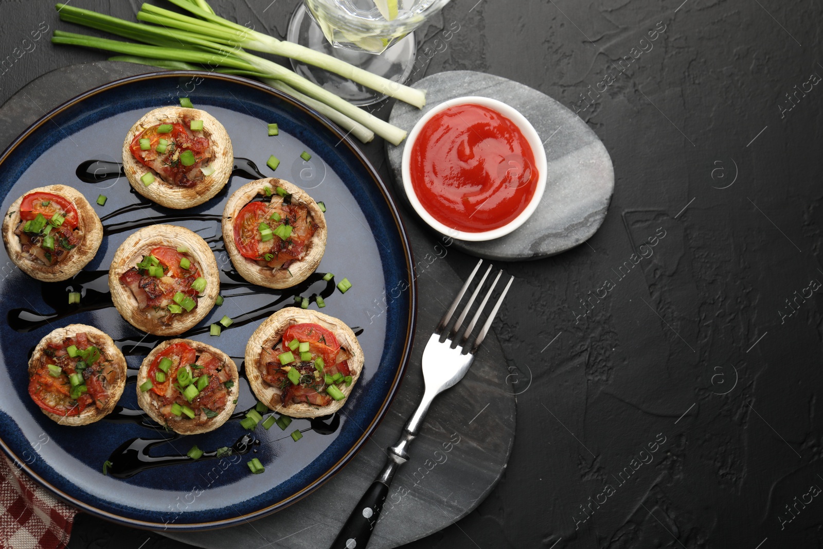 Tasty stuffed mushrooms served on black table, flat lay Photo of Tasty stuffed mushrooms served on black table, flat lay