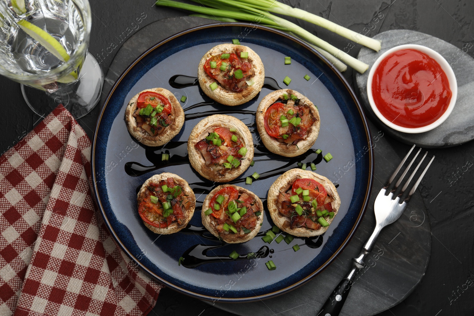 Tasty stuffed mushrooms served on black table, flat lay Photo of Tasty stuffed mushrooms served on black table, flat lay