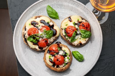 Photo of Tasty stuffed mushrooms and drink served on black table, top view