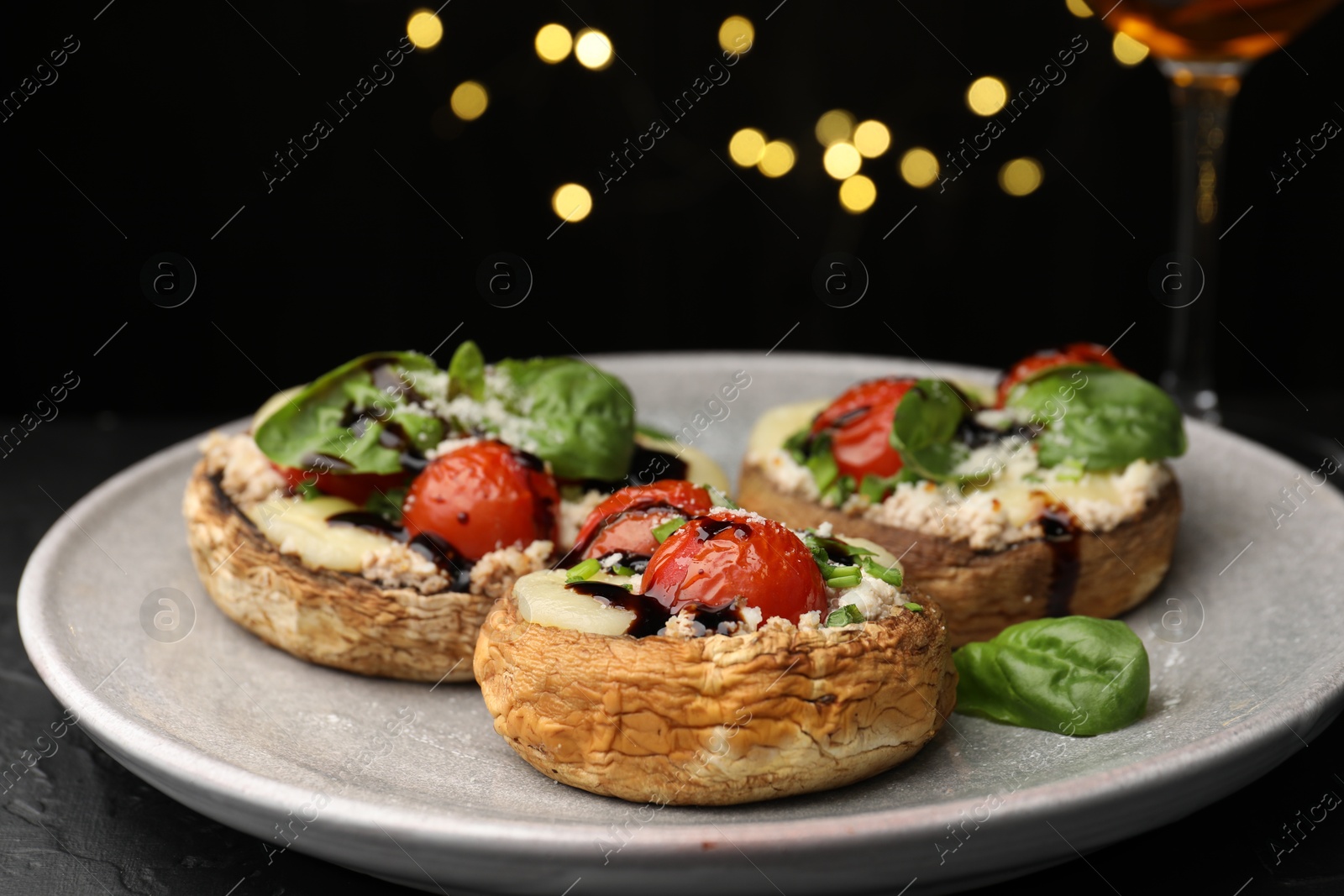 Tasty stuffed mushrooms served on black table against blurred background, closeup. Bokeh effect Photo of Tasty stuffed mushrooms served on black table against blurred background, closeup. Bokeh effect