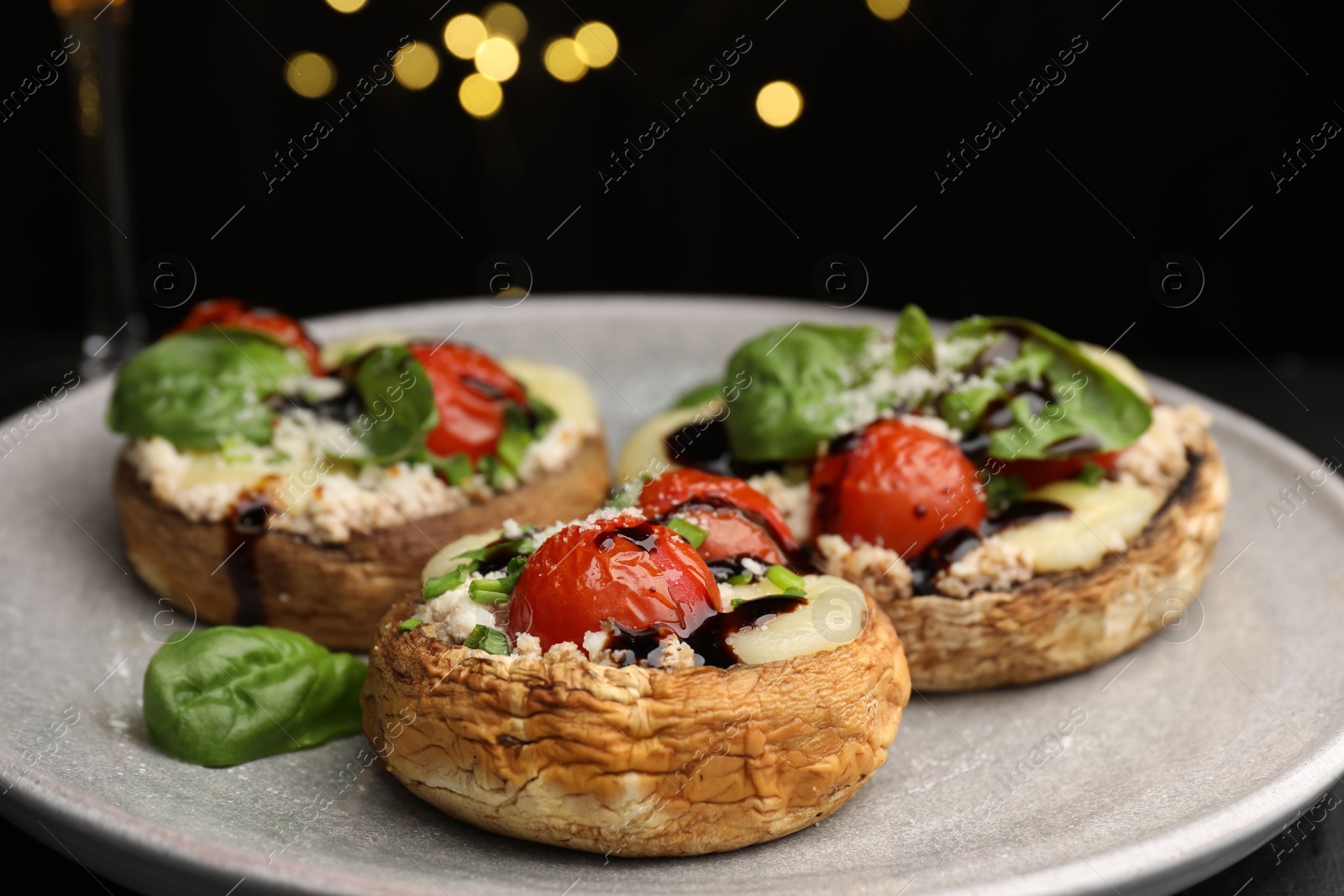 Tasty stuffed mushrooms served on black table against blurred background, closeup. Bokeh effect Photo of Tasty stuffed mushrooms served on black table against blurred background, closeup. Bokeh effect