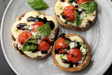 Photo of Tasty stuffed mushrooms served on black table, top view