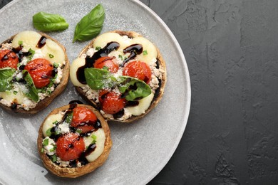 Photo of Tasty stuffed mushrooms served on black table, top view. Space for text