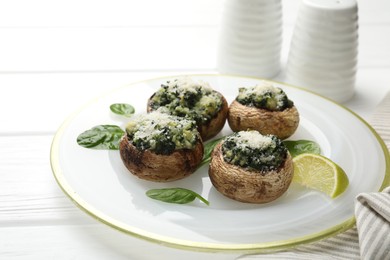 Photo of Tasty stuffed mushrooms served on white wooden table, closeup
