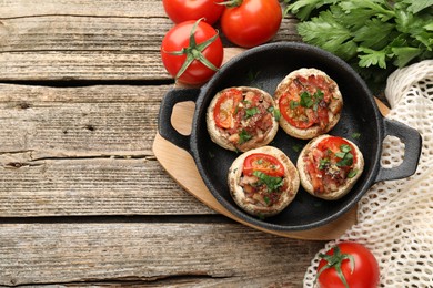 Photo of Tasty stuffed mushrooms served on wooden table, flat lay. Space for text