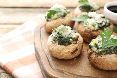 Photo of Tasty stuffed mushrooms served on wooden table, closeup