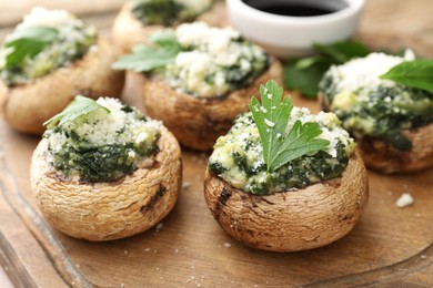 Photo of Tasty stuffed mushrooms served on wooden table, closeup