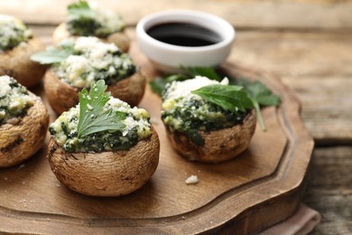 Photo of Tasty stuffed mushrooms served on wooden table, closeup