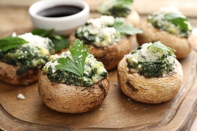 Photo of Tasty stuffed mushrooms served on wooden table, closeup