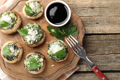 Photo of Tasty stuffed mushrooms served on wooden table, top view