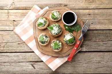 Photo of Tasty stuffed mushrooms served on wooden table, top view