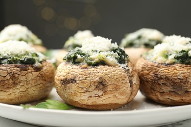 Photo of Tasty stuffed mushrooms served on white table against blurred background, closeup