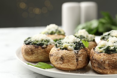 Photo of Tasty stuffed mushrooms served on white table against blurred background, closeup
