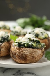 Photo of Tasty stuffed mushrooms served on white table against blurred background, closeup
