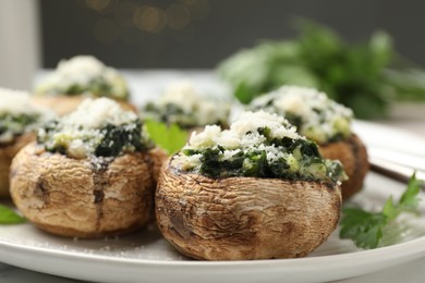 Photo of Tasty stuffed mushrooms served on white table against blurred background, closeup