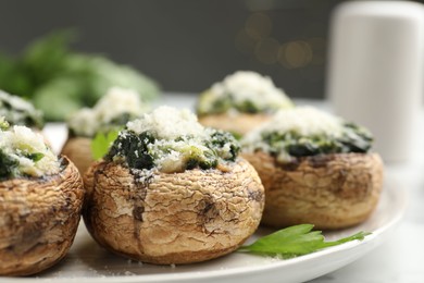 Photo of Tasty stuffed mushrooms served on white table against blurred background, closeup