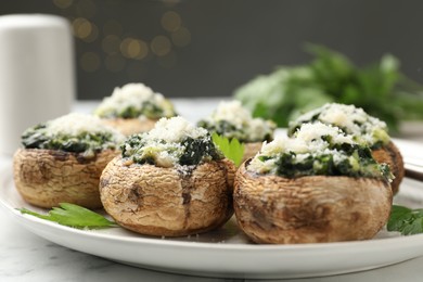Photo of Tasty stuffed mushrooms served on white table against blurred background, closeup