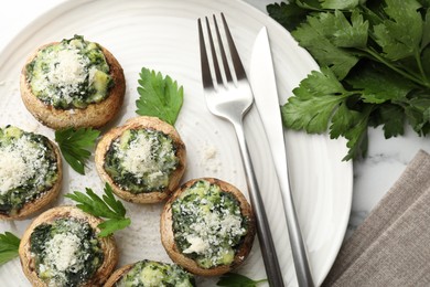 Photo of Tasty stuffed mushrooms served on white table, flat lay