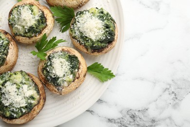 Photo of Tasty stuffed mushrooms served on white marble table, top view. Space for text