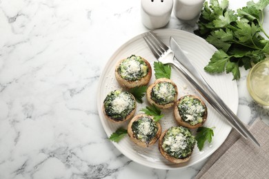 Photo of Tasty stuffed mushrooms served on white marble table, flat lay. Space for text