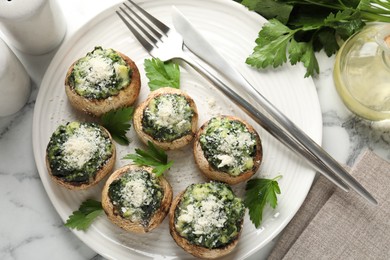Photo of Tasty stuffed mushrooms served on white marble table, flat lay