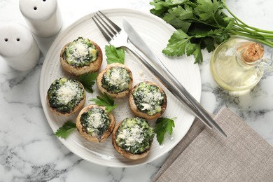 Photo of Tasty stuffed mushrooms served on white marble table, flat lay