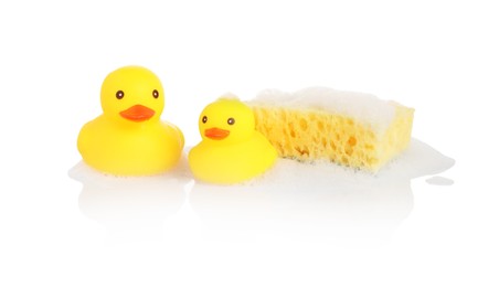 Photo of Cute rubber ducks and sponge with foam on mirror surface against white background