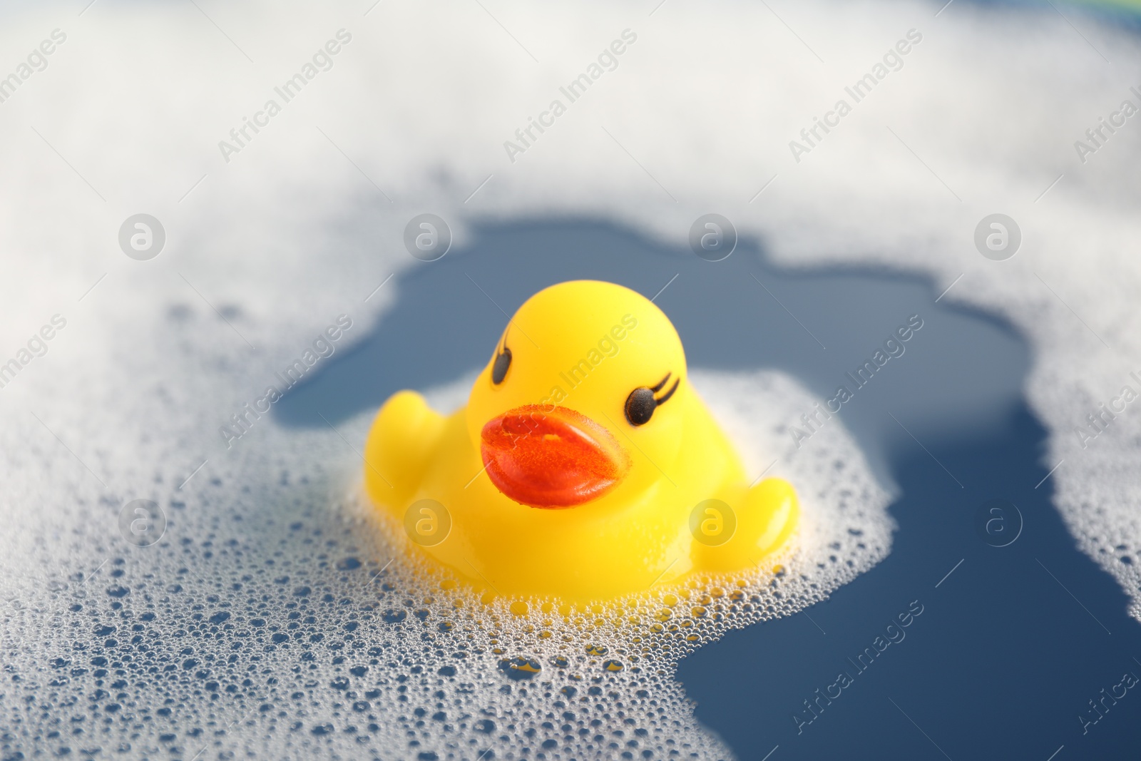 Cute rubber duck floating in water with bubbles, closeup Photo of Cute rubber duck floating in water with bubbles, closeup