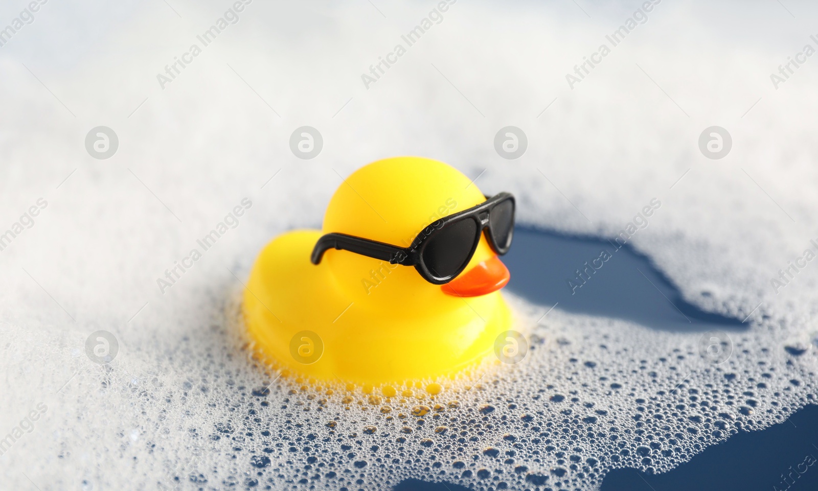 Cute rubber duck floating in water with bubbles, closeup Photo of Cute rubber duck floating in water with bubbles, closeup
