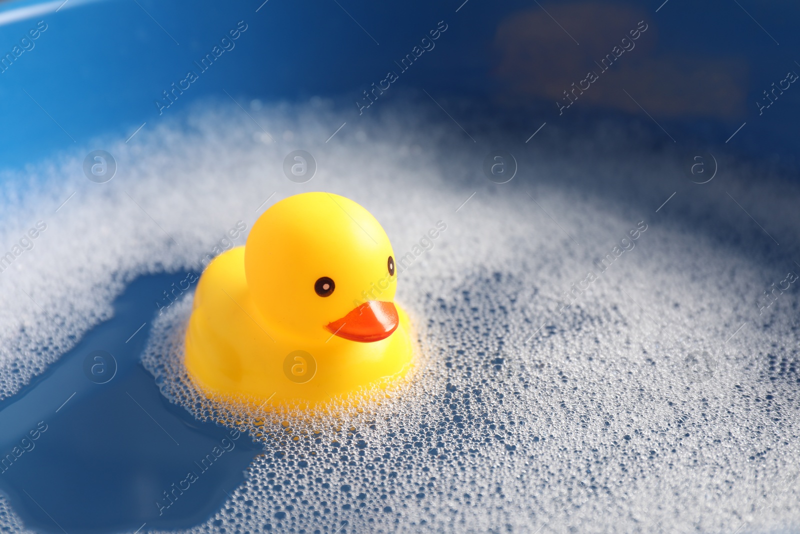 Cute rubber duck floating in water with bubbles, closeup Photo of Cute rubber duck floating in water with bubbles, closeup