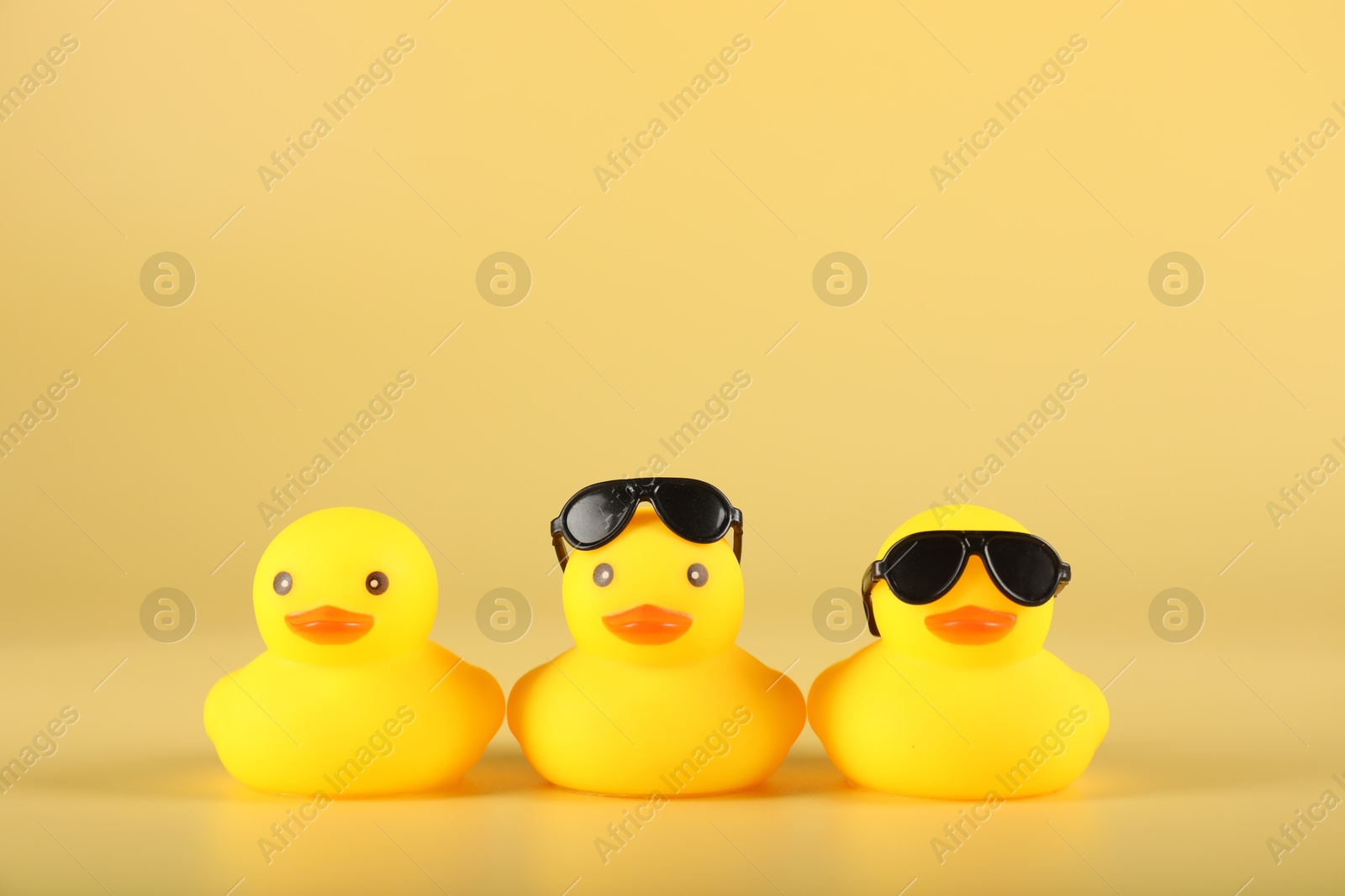 Three cute rubber ducks on yellow background Photo of Three cute rubber ducks on yellow background