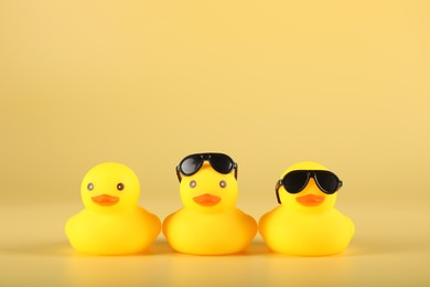 Photo of Three cute rubber ducks on yellow background