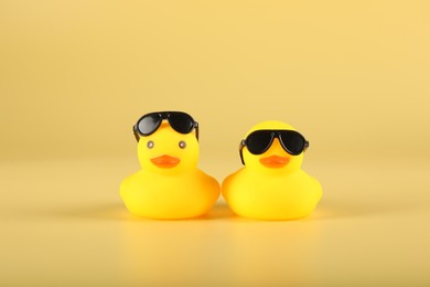 Photo of Cute rubber ducks with sunglasses on yellow background