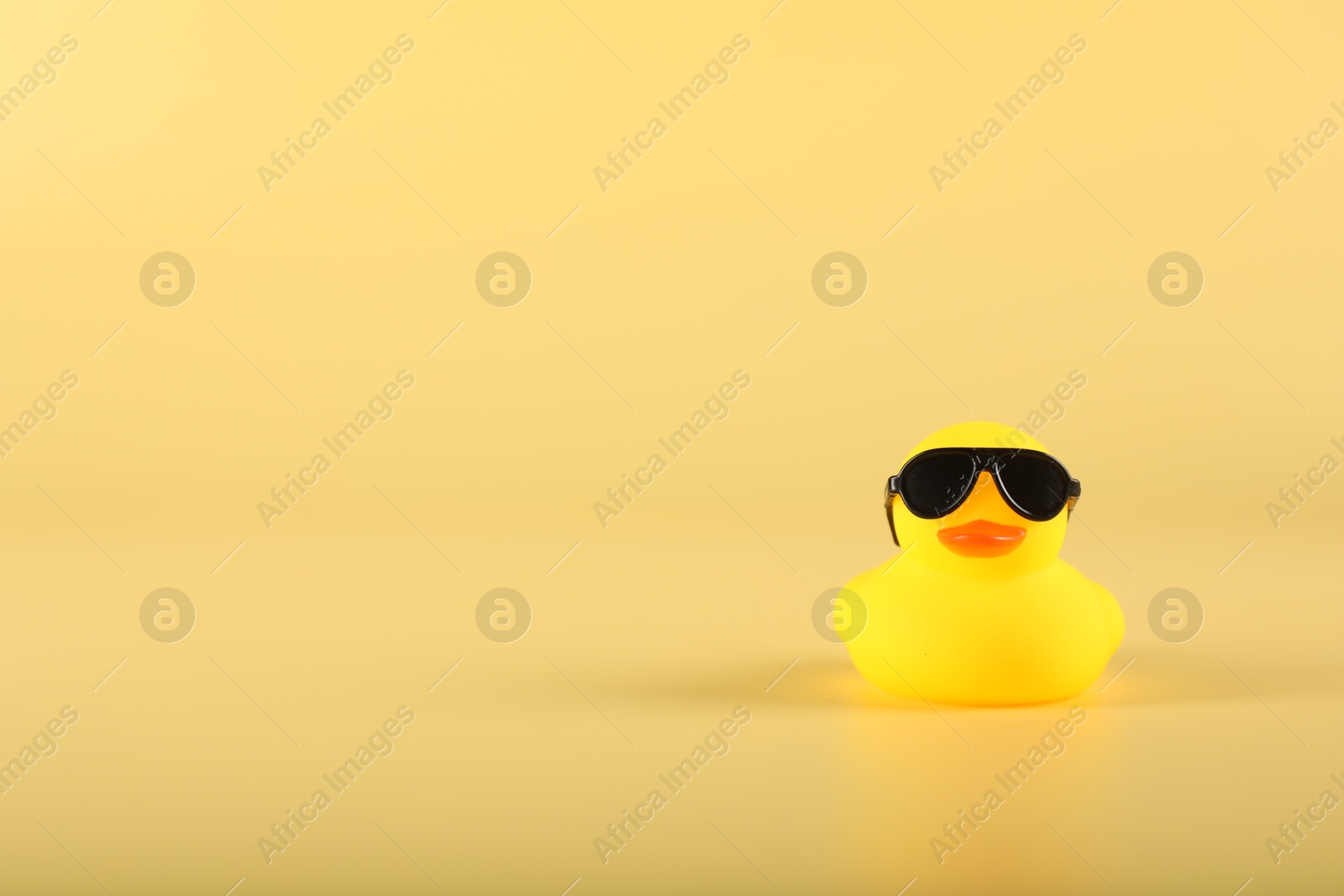 Cute rubber duck with sunglasses on yellow background, space for text Photo of Cute rubber duck with sunglasses on yellow background, space for text