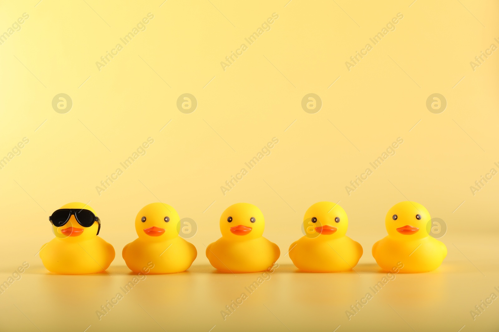 Many cute rubber ducks on yellow background Photo of Many cute rubber ducks on yellow background