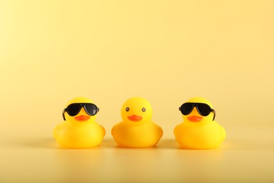 Photo of Three cute rubber ducks on yellow background